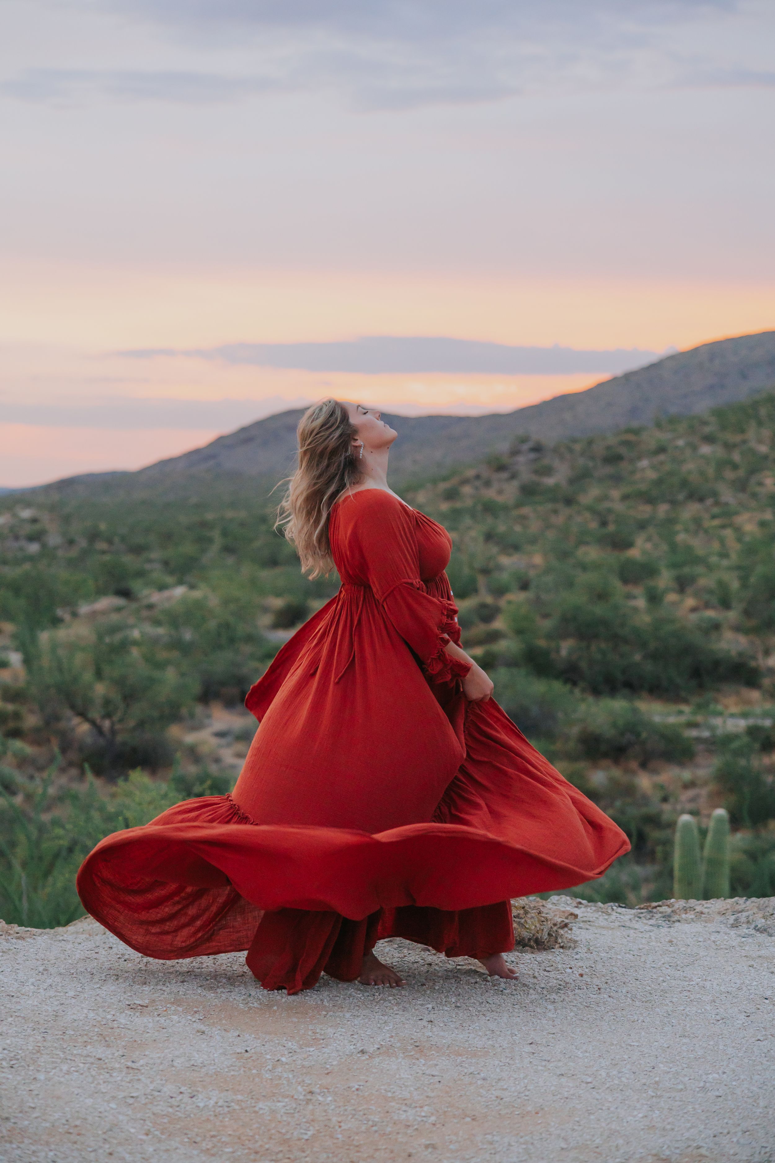 A red dress spins dramatically against a desert mountain backdrop during sunset.