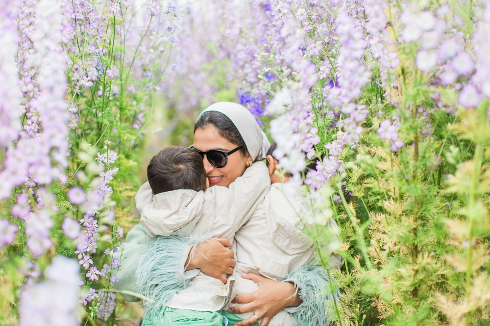 A tender embrace shared in a garden of blooming purple delphinium flowers on a bright spring day at the confetti fields in Worcestershire