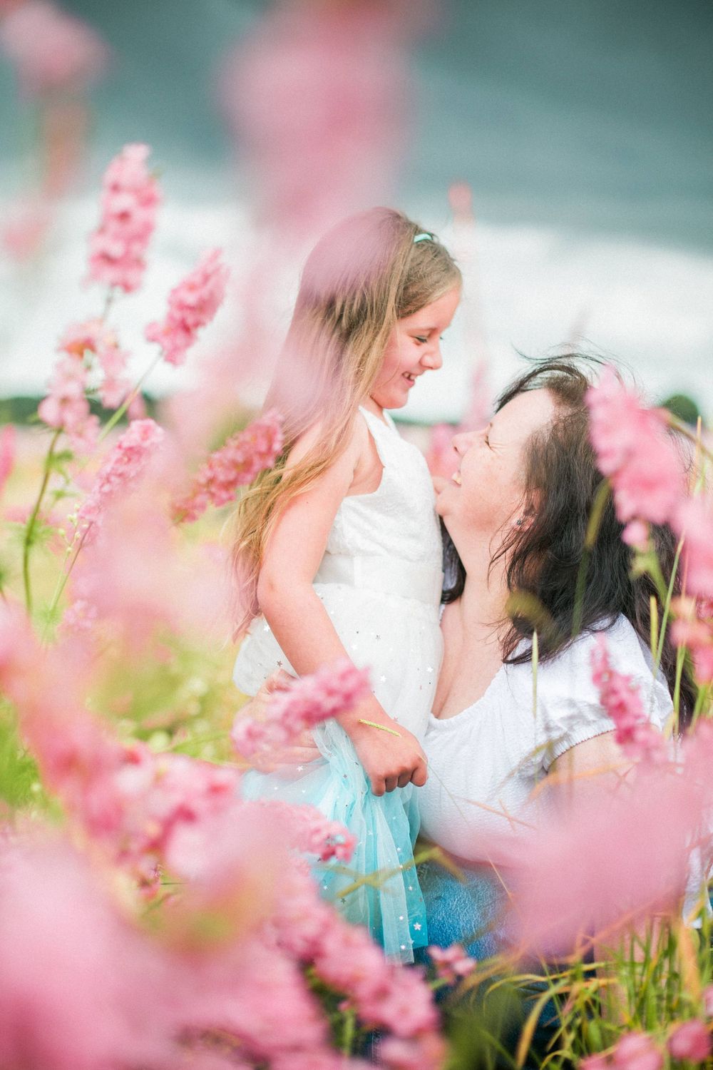 Two people share a tender moment among blooming pink flowers in a dreamy outdoor setting at confetti fields by Hayley Elizabeth photography