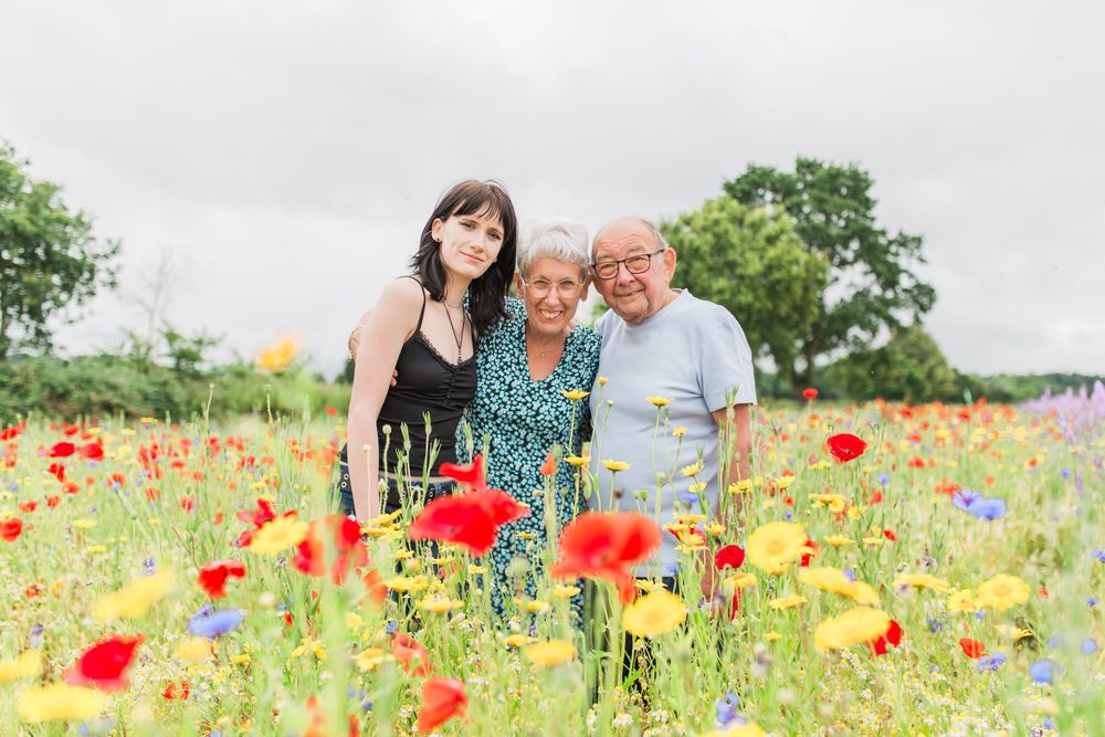 teen and grandparents together in a vibrant field of red poppies and wildflowers on a cloudy summer day at the confetti fields cotswold