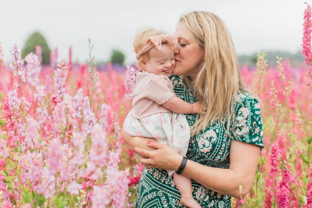 A tender embrace between parent and child amidst a field of pink flowers on a summer day at confetti fields by Hayley Elizabeth photography