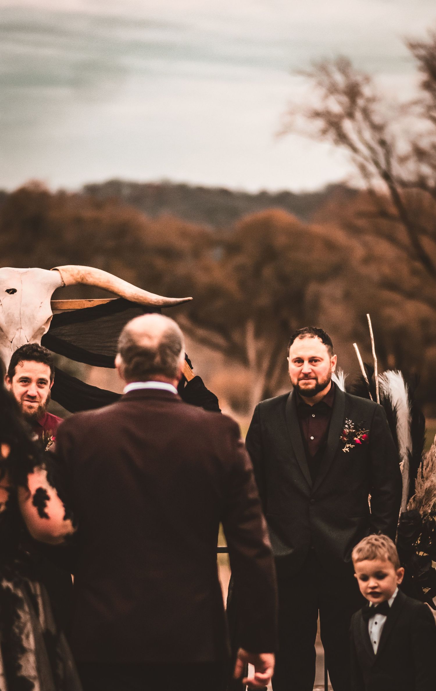 Wedding ceremony outdoors with animal skull decor and autumn trees in background.