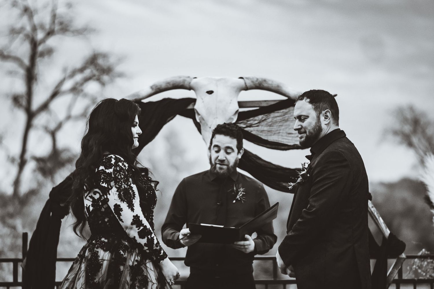 Black and white wedding ceremony photo with rustic decor and dramatic emotional moment.