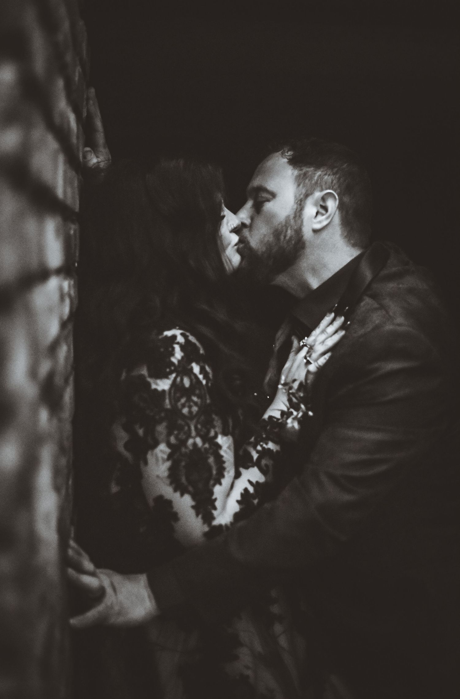 An artistic black and white portrait of a couple in formal wear sharing a romantic moment.