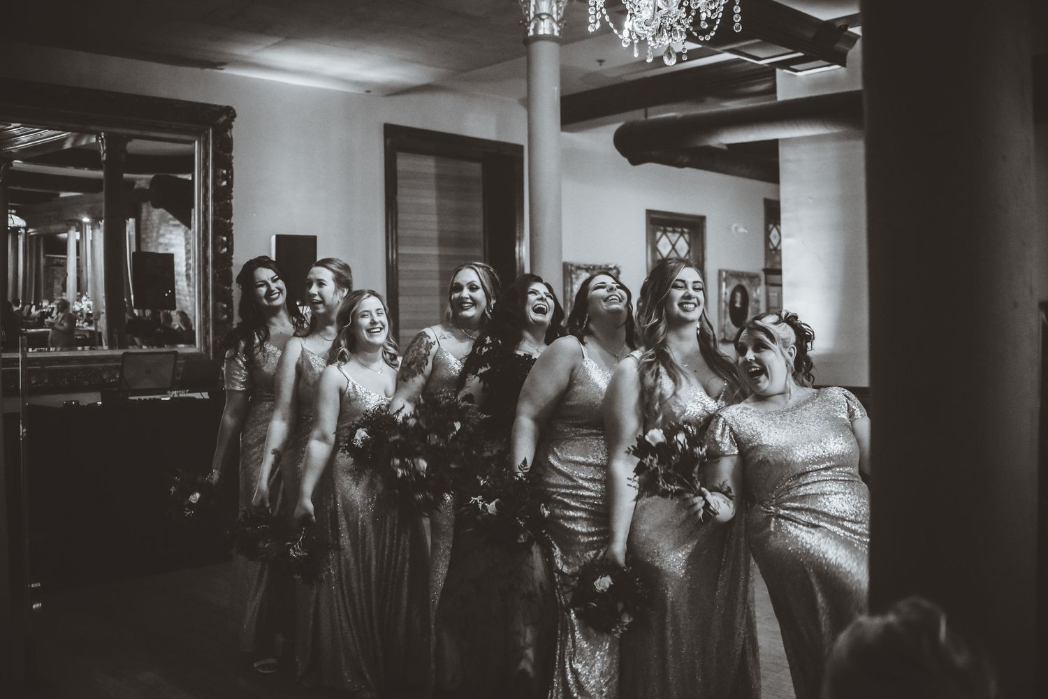 Bridal party poses together in an elegant black and white photograph at a wedding venue.