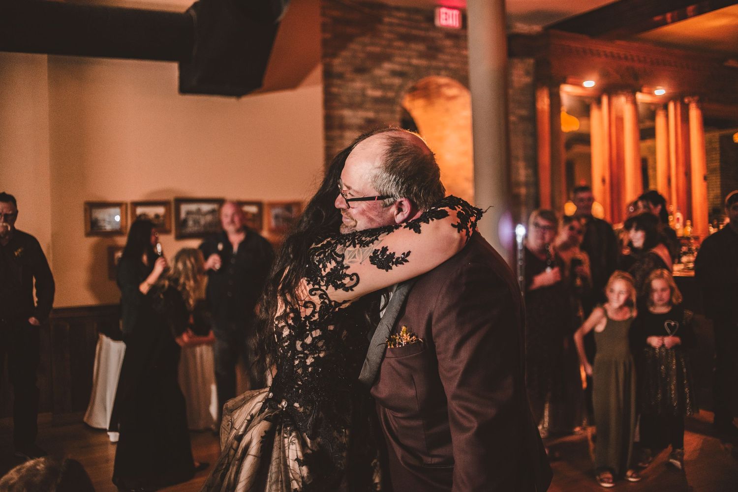 An intimate dance moment captured in a venue with exposed brick and warm lighting.