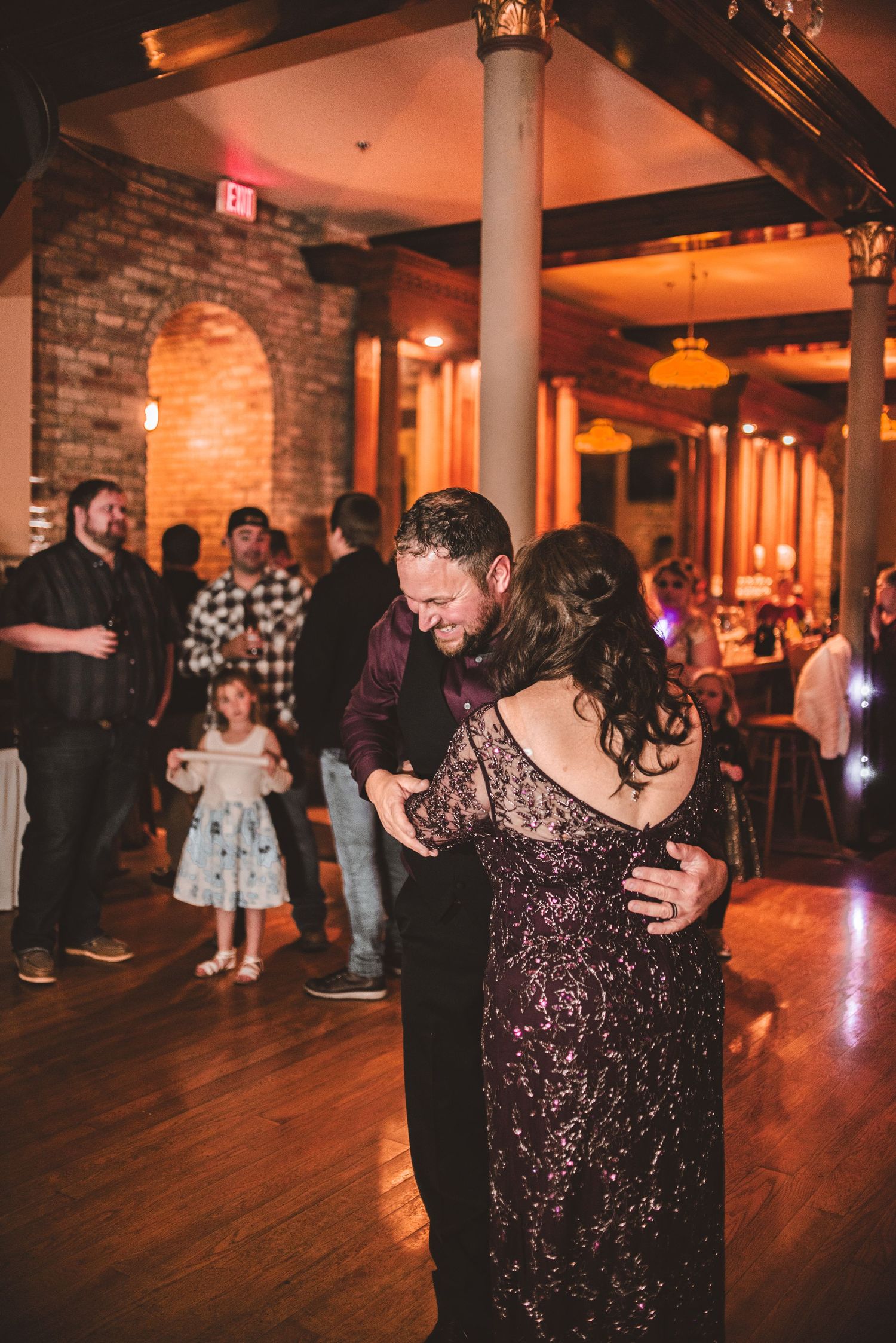 Dancing at an elegant indoor venue with exposed brick walls and ornate columns.