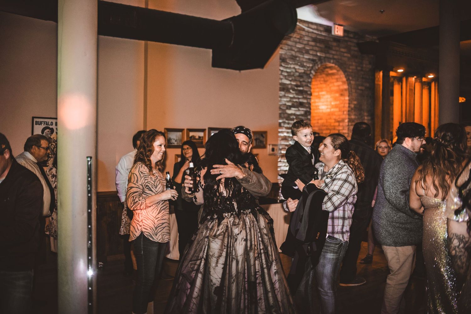 Guests mingling and celebrating at an indoor reception with stone accent walls.