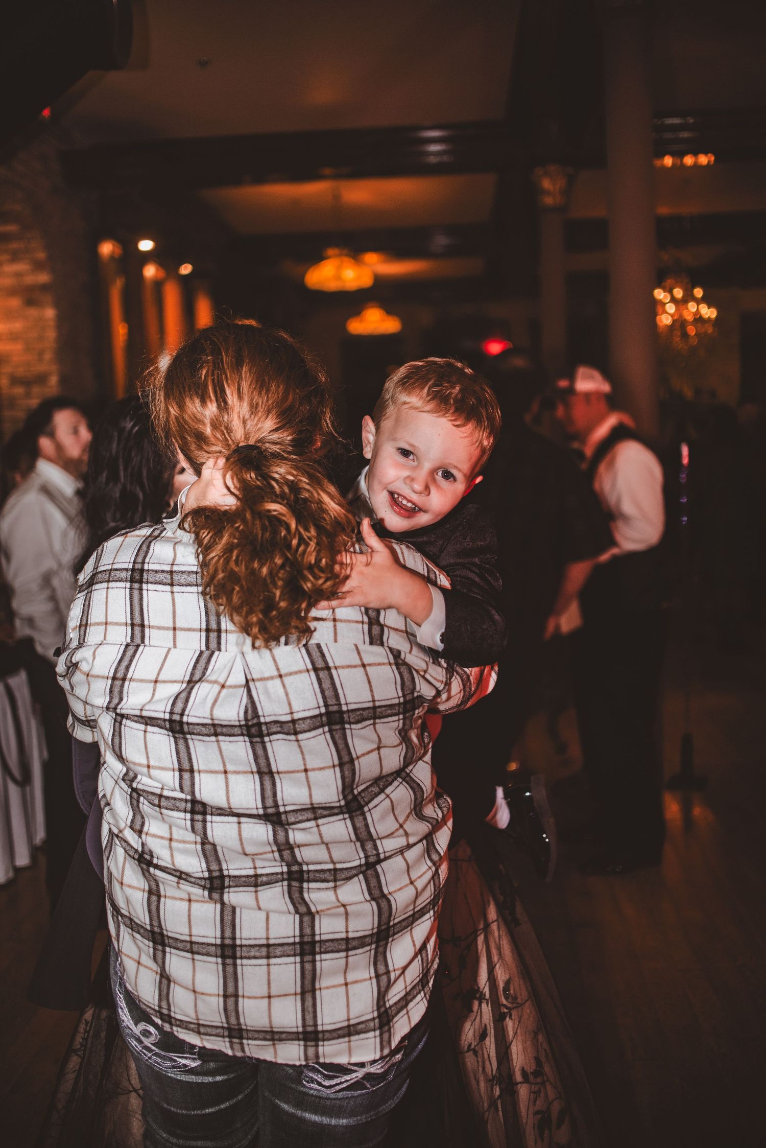 Child smiling while dancing with adult at indoor celebration.