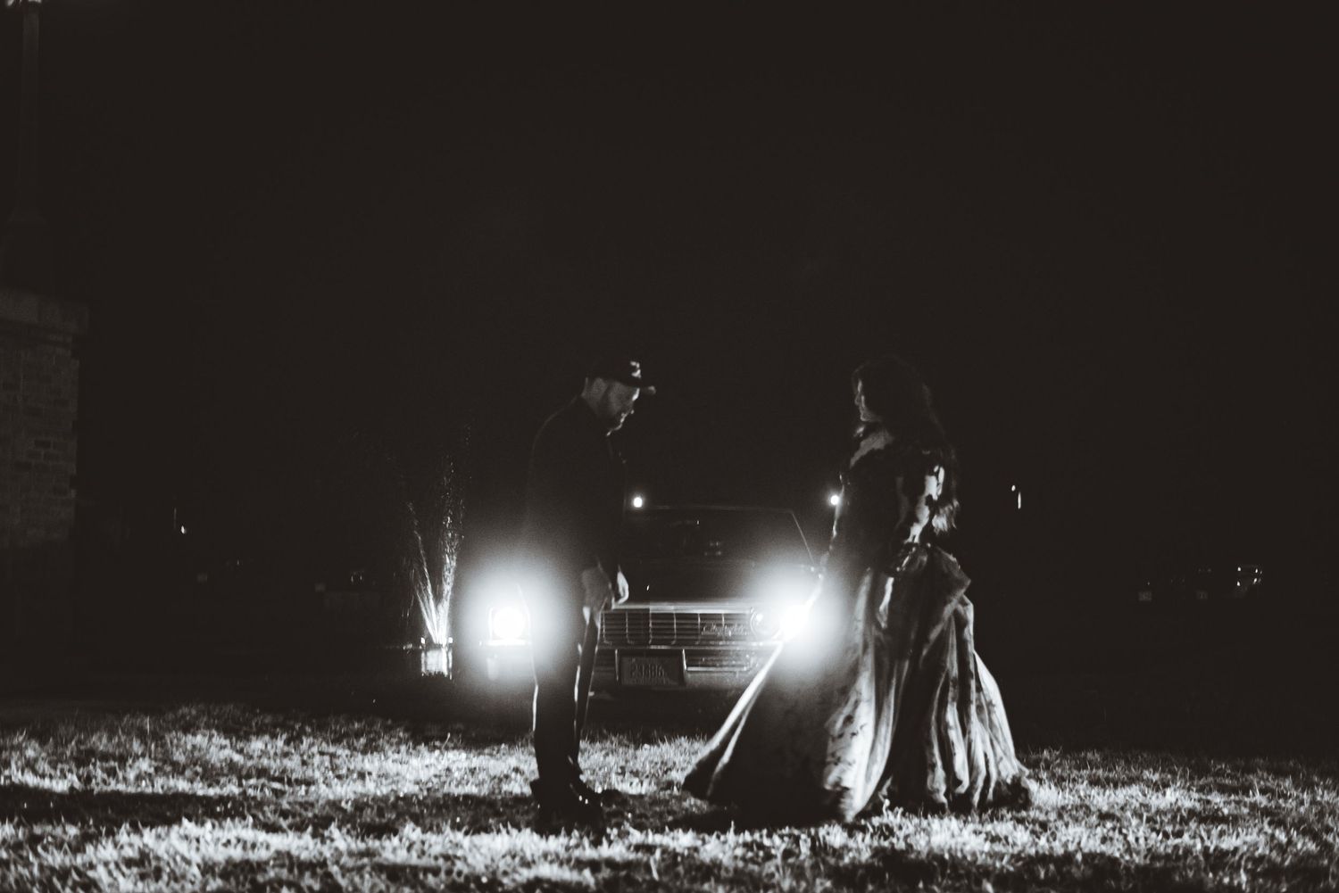 Black and white photo of dancing silhouettes illuminated by car headlights.