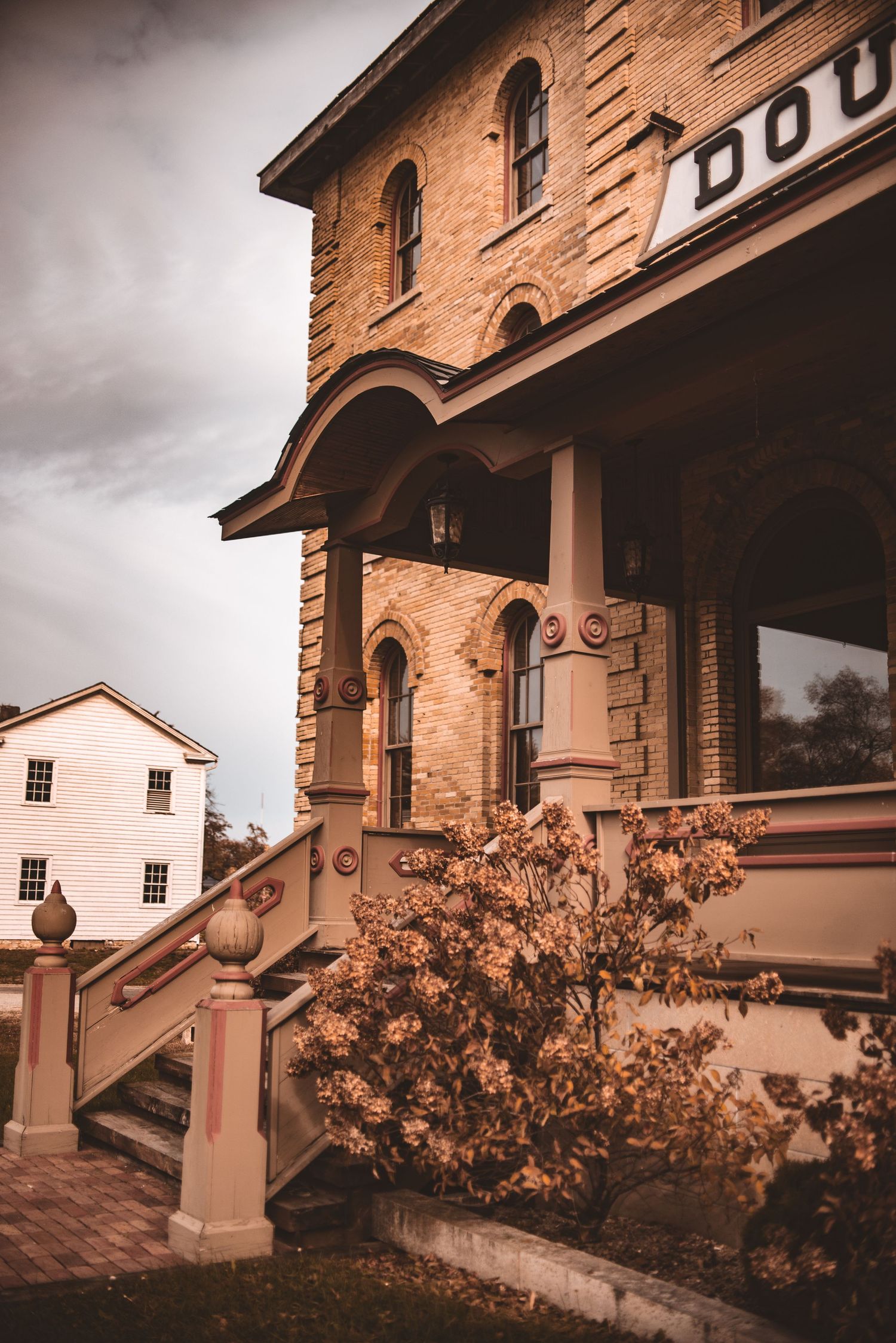 A sepia-toned architectural view of the historic Dousman House with ornate pillars and archways.