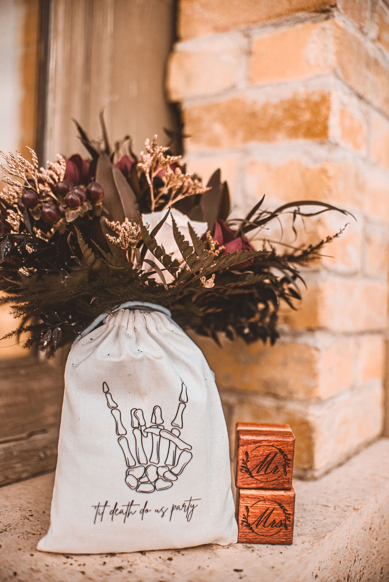 Gothic-themed wedding accessories with skeleton hand design on white bag and wooden ring boxes.
