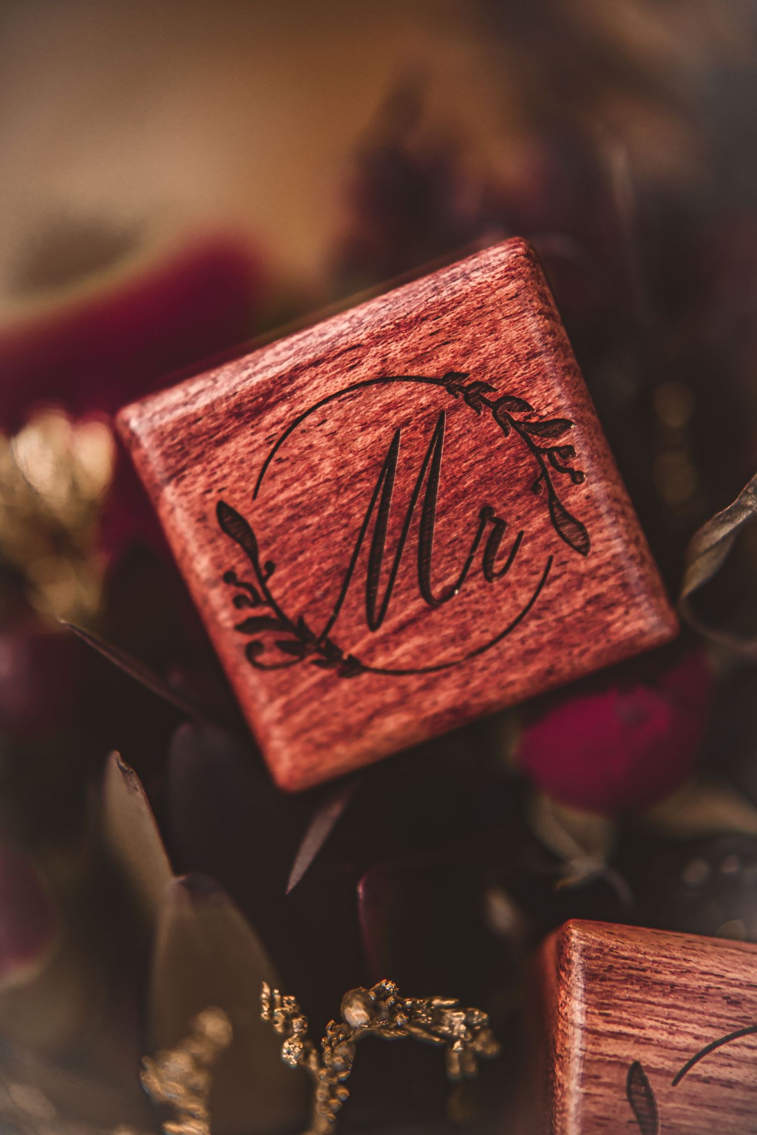 Close-up of a wooden ring box with monogram M design in burgundy finish.