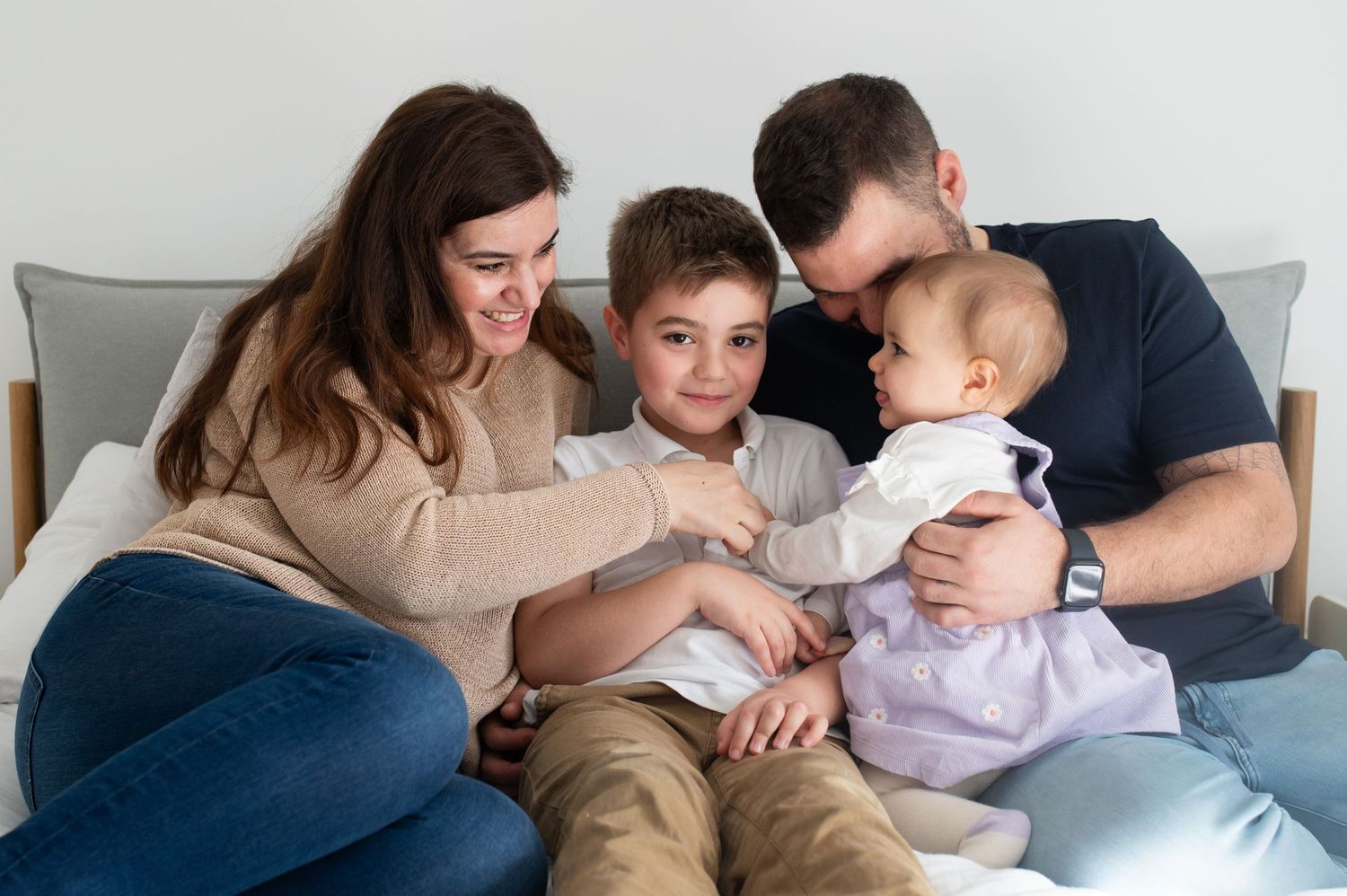 Family of 4 lying on a bed enjoying some time together - Sarah Frame Photography - Newborn - Surrey