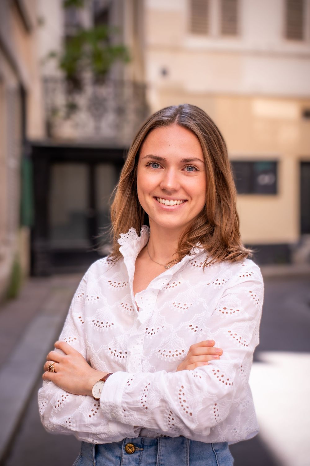 Une jeune fille souriante qui pose pour un portrait Linkedin dans une rue de Bruxelles