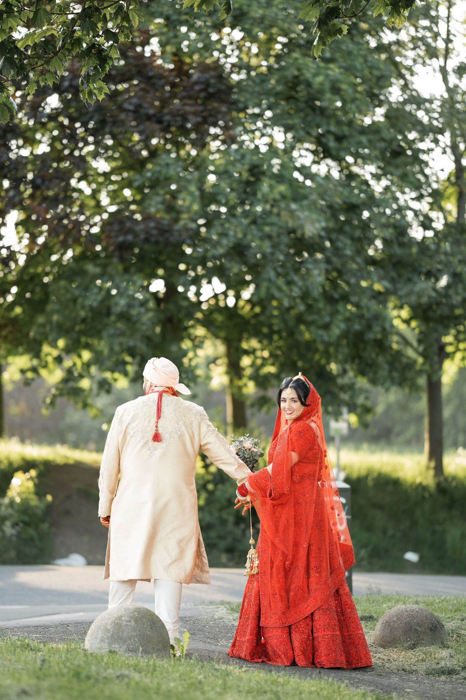 Newly wedded bride and groom happliy married posing in a a gorgeous green garden smiling at the cameraman