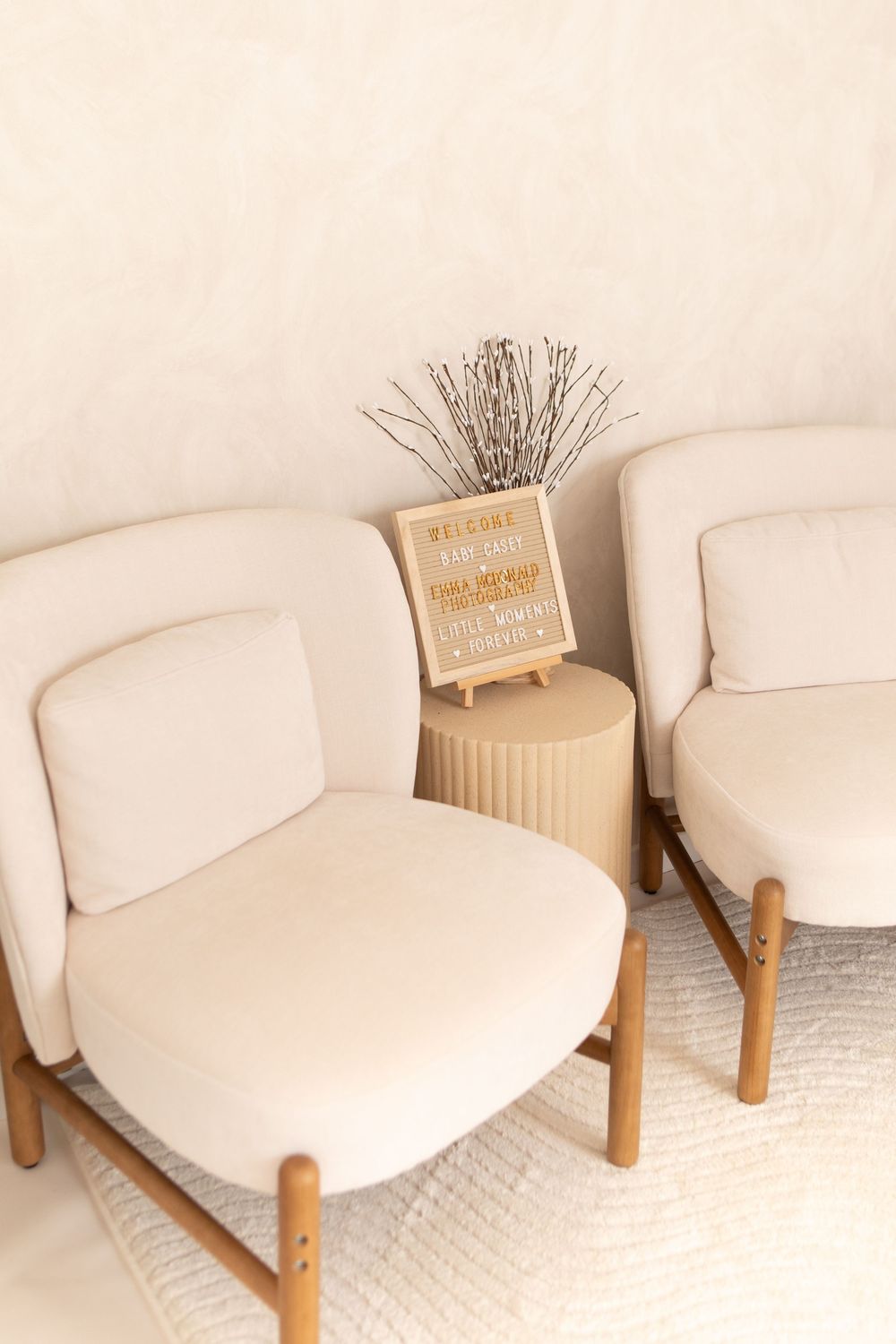 Modern cream-colored accent chair with wooden legs shown from multiple angles on white carpet.