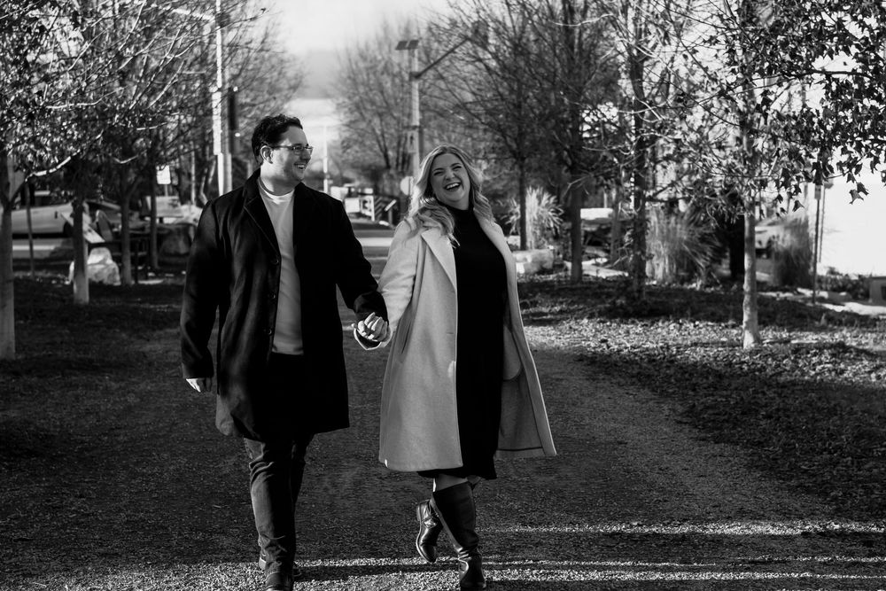 Black and white engagement photos showing couple walking through autumn trees.