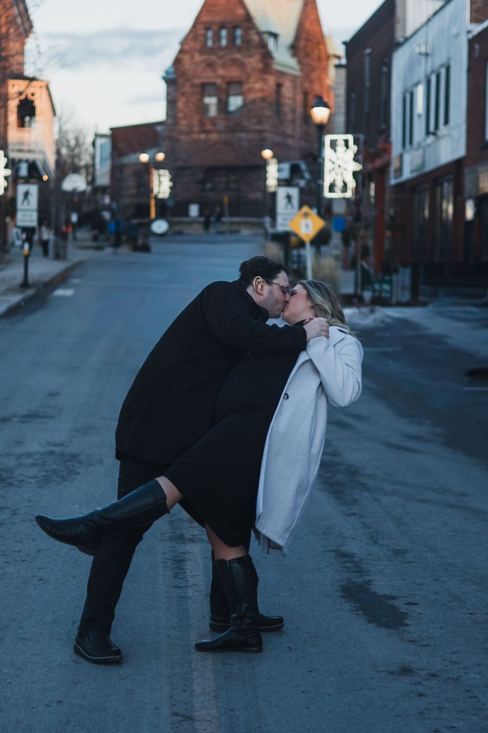 A romantic dip kiss captured on a city street at dusk.