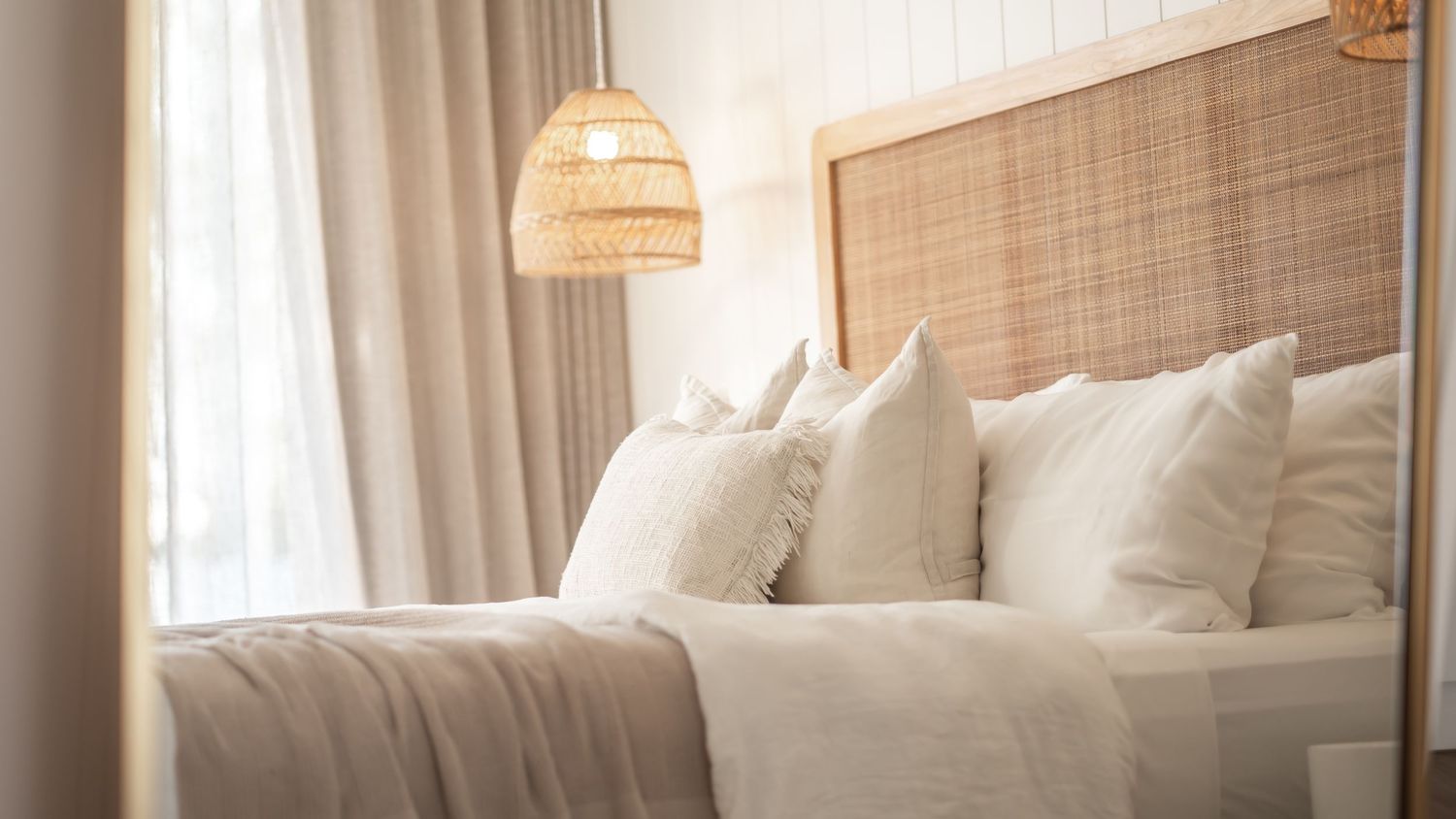Cozy hotel bedroom with rattan headboard and soft white bedding.