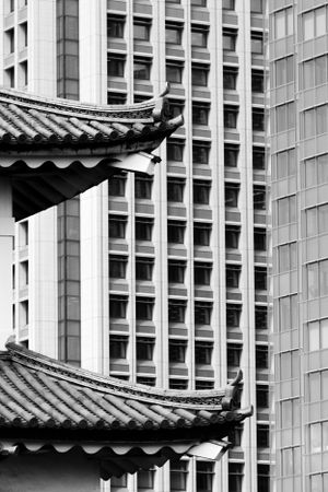 Traditional Chinese pagoda roofs contrast against modern office building architecture in an urban setting.