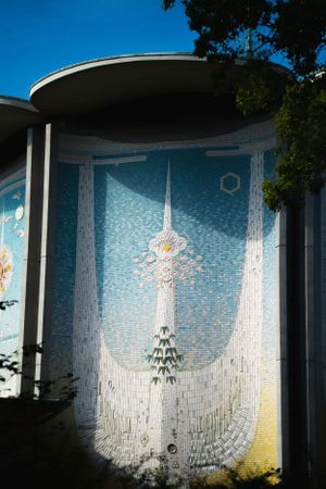 Large curved wall mural featuring blue mosaic tiles with white vertical designs.