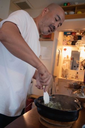 Someone cooking and seasoning food in a cast iron pan in a home kitchen.