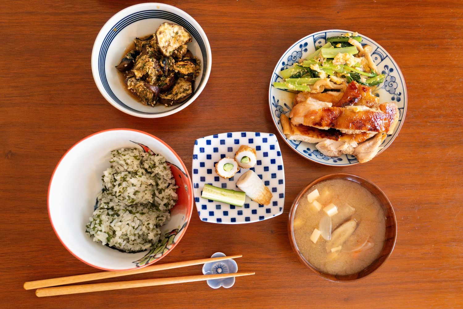 Traditional Japanese meal spread on wooden table with miso soup, rice, and side dishes.