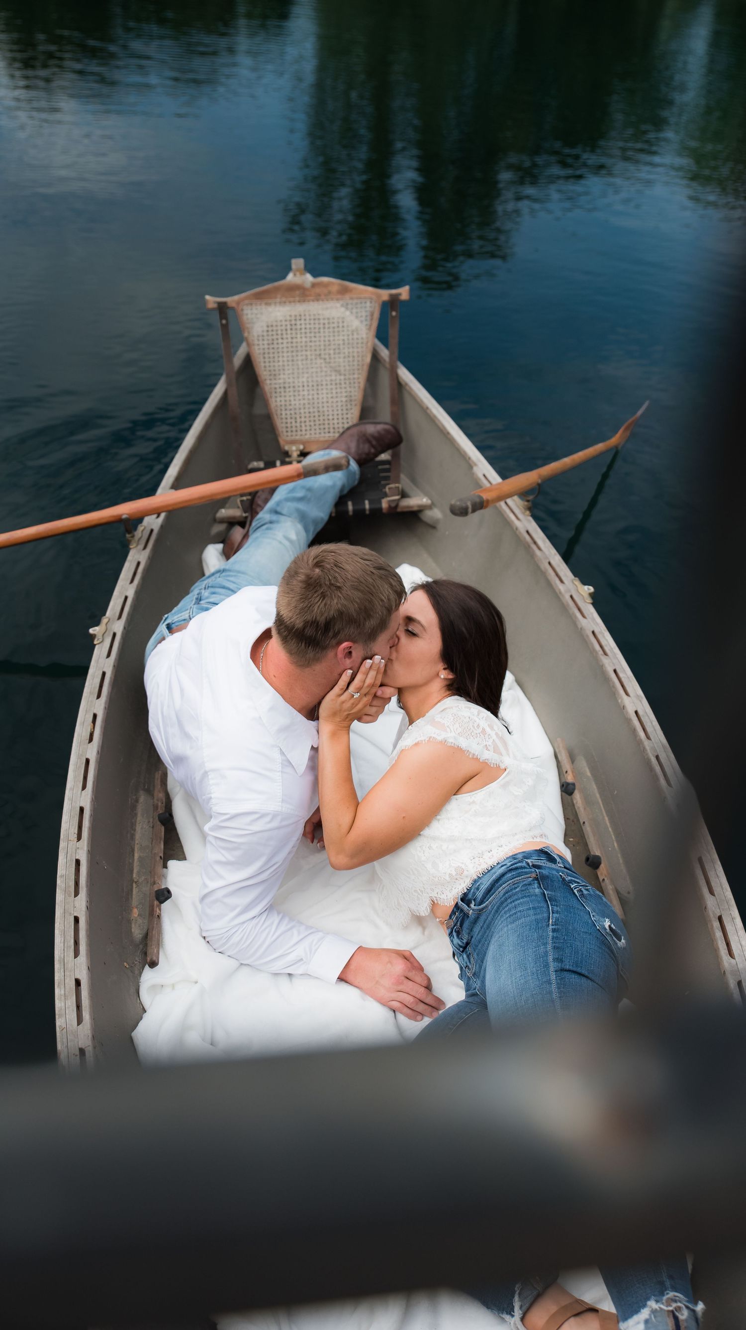 An engaged couple laying down kissing in a canoe in the pond at Whippoorwill Manor in Mayfield, KY.