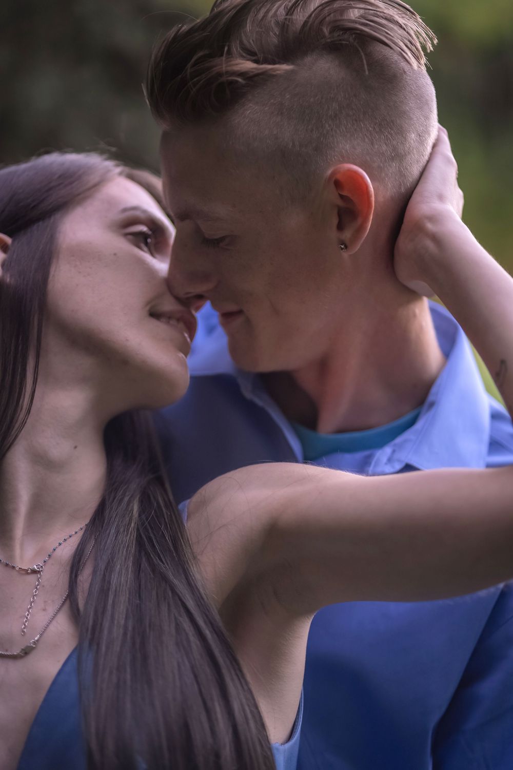A romantic couple shares an intimate moment outdoors in a natural setting.