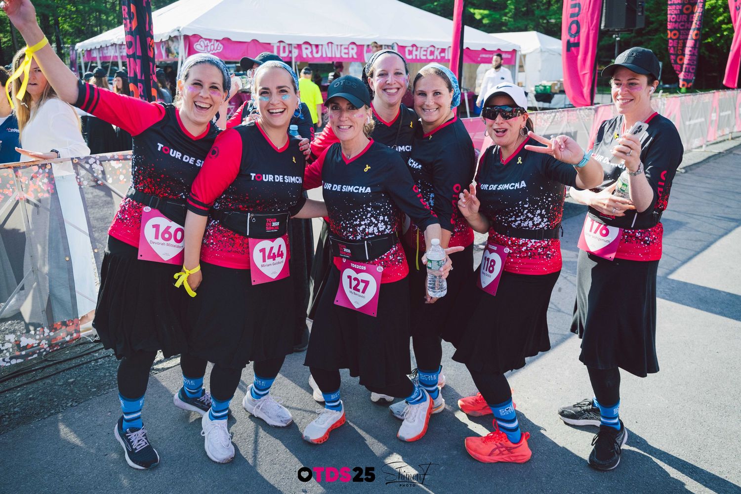 Participants in matching pink and black athletic wear pose together at a sporting event.