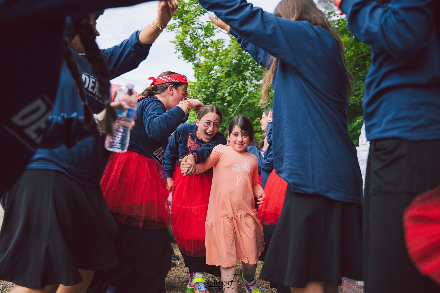 People gathered at an outdoor event wearing navy and red outfits.
