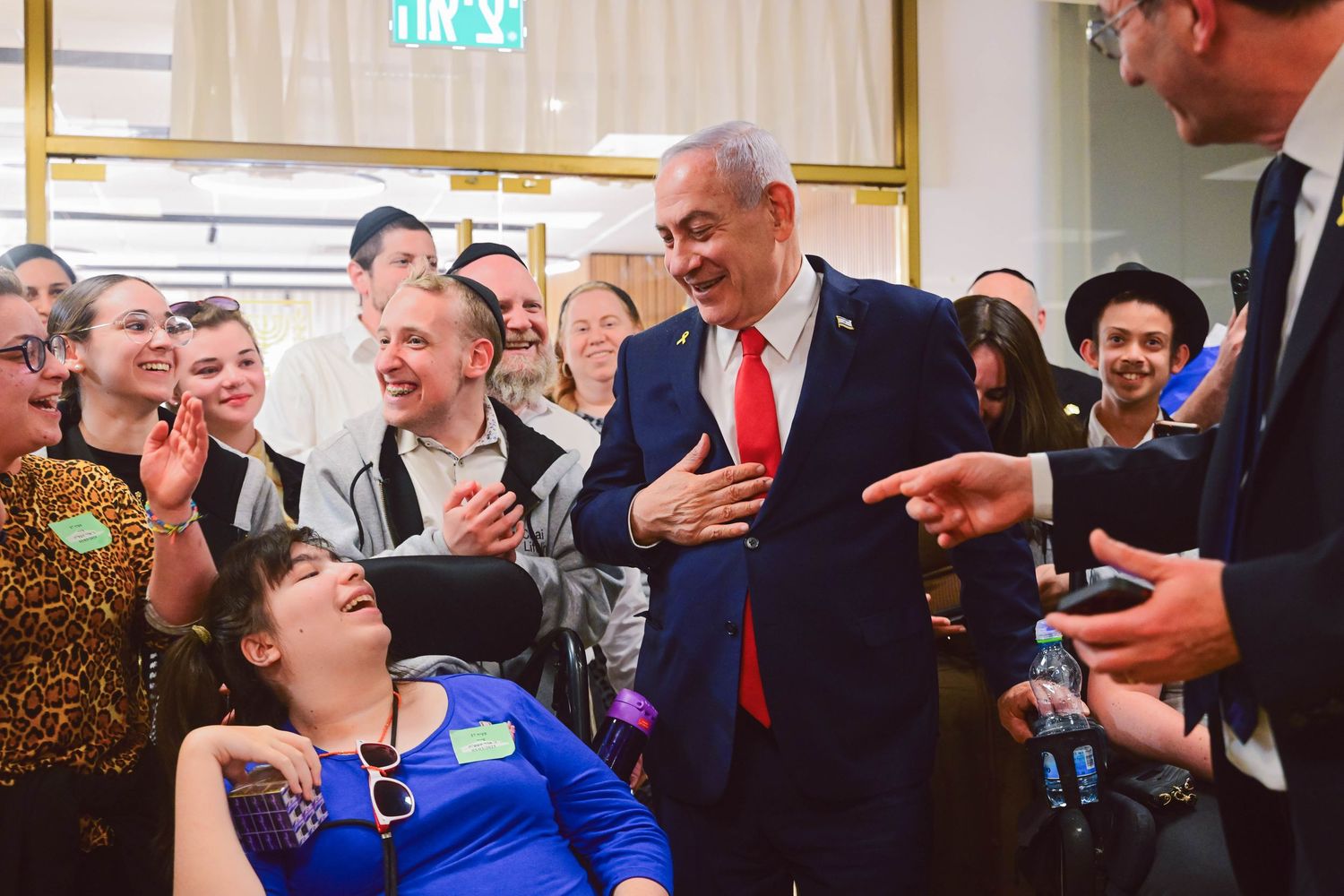 People laughing and socializing at an indoor event with formal attire.