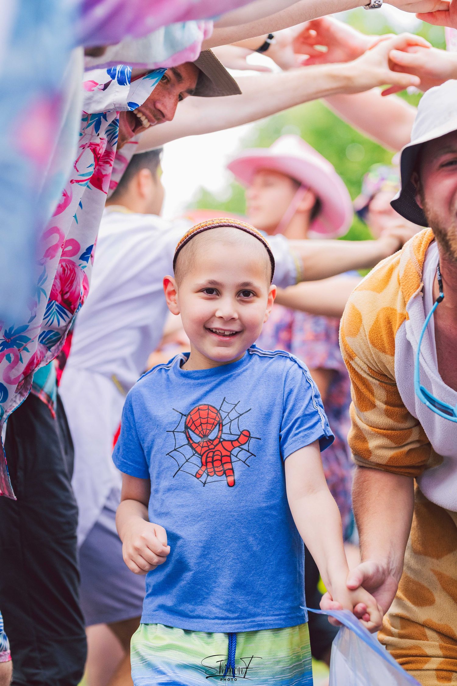 Children enjoying a colorful outdoor celebration with raised hands and bright decorations.
