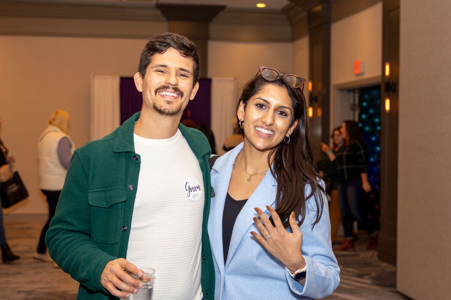 Two attendees at a formal event pose together, one wearing a green jacket and one in a light blue blazer.