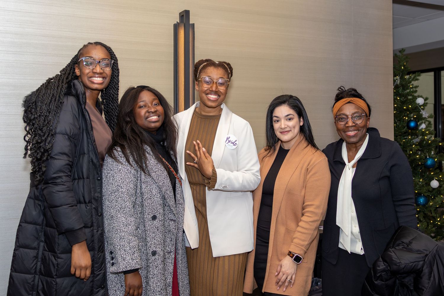 Five stylishly dressed attendees pose together at a professional event.