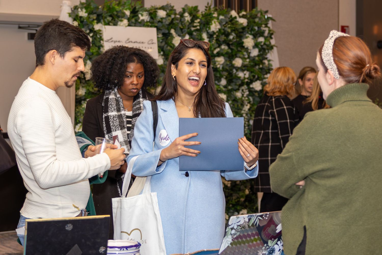 Group of attendees review documents at an event with floral decorations in the background.