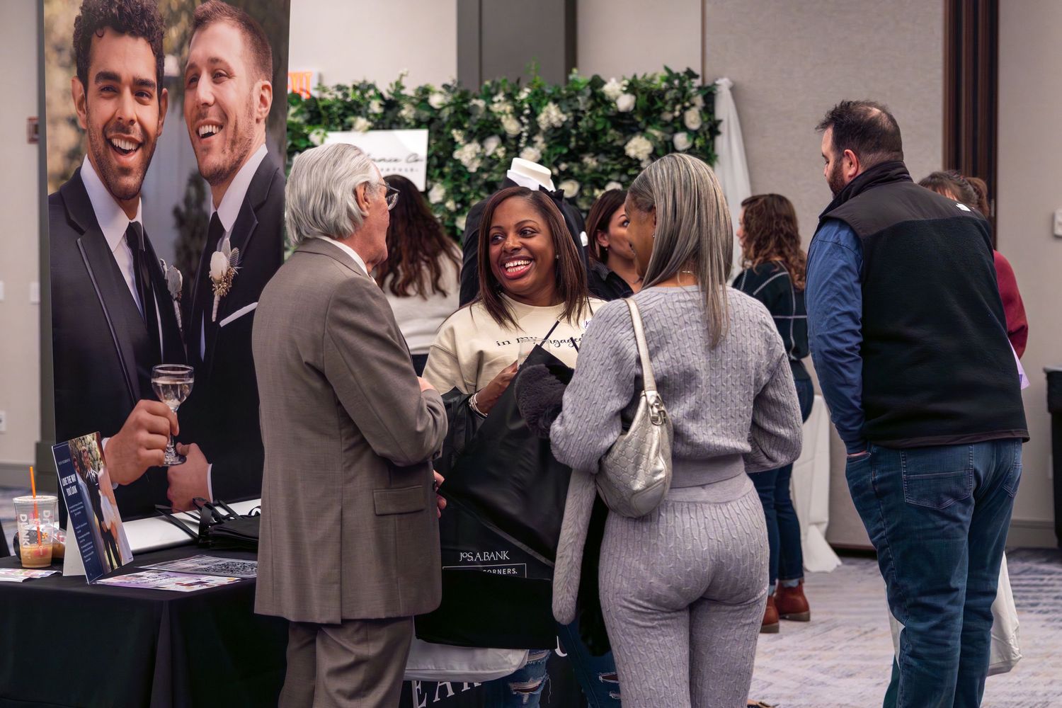 Group of people networking and socializing at an indoor event with display booths.