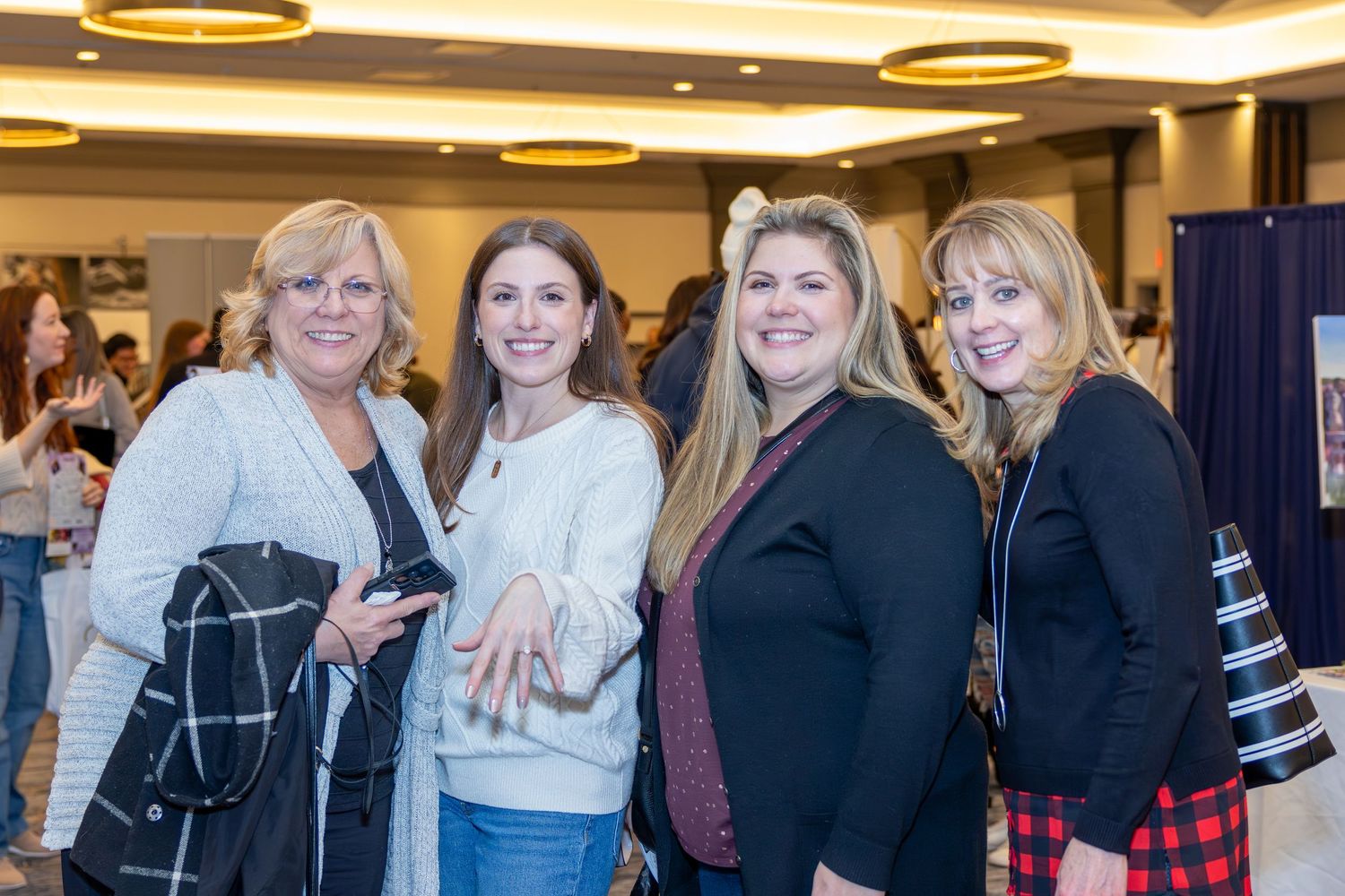 Four attendees pose together at an indoor event wearing casual winter attire.