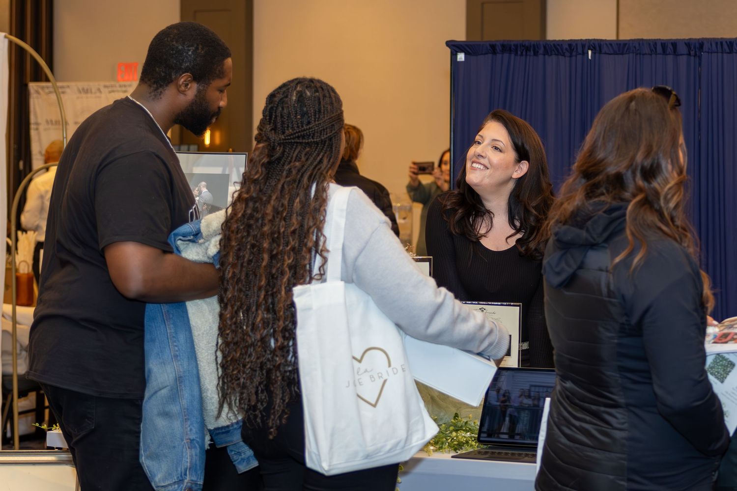 Attendees interact at a vendor booth during an indoor expo event.