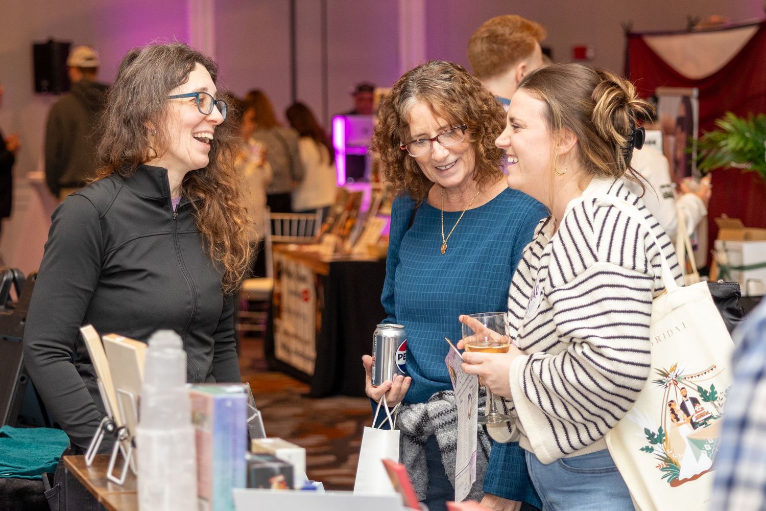 Attendees mingle and network at an upscale social event with pink lighting and floral arrangements.