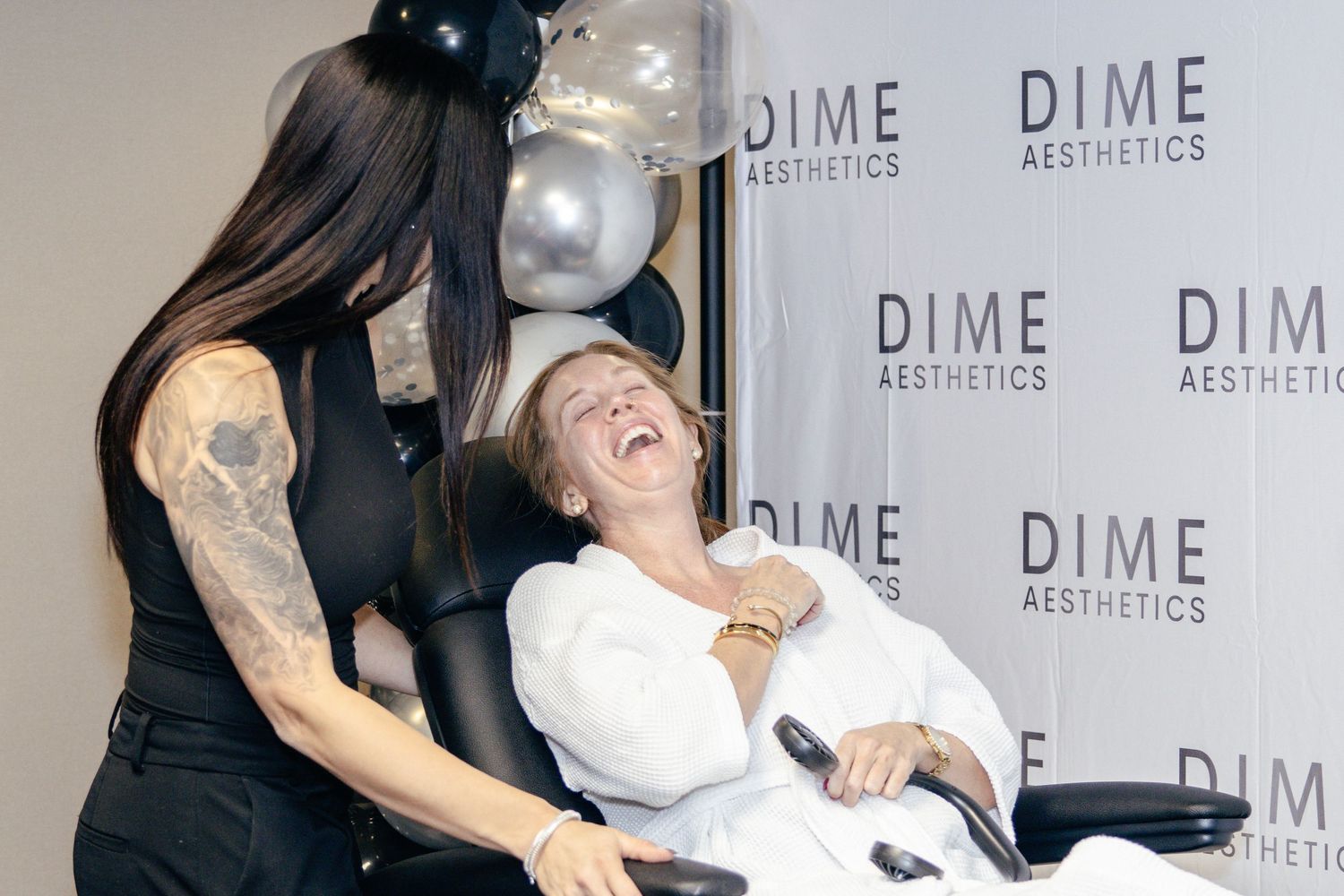 Event celebration with black and silver balloons against a branded DIME Aesthetics backdrop.