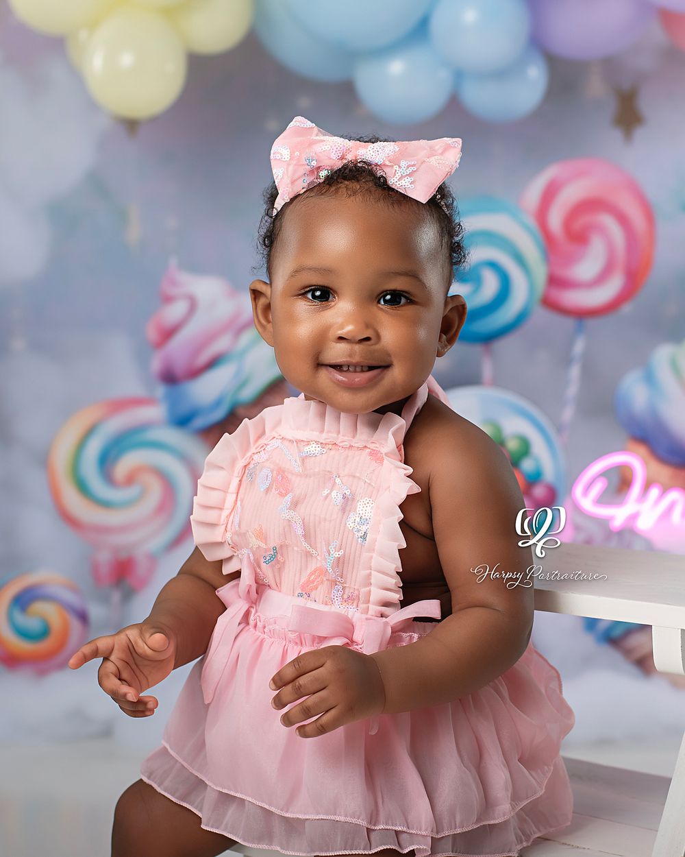 Smiling baby girl first birthday photoshoot; best professional photographer Lexington, SC; Cake Smash Session pastel colors with candy