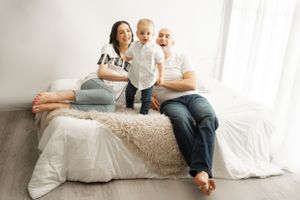 Happy family lounging on bed with fluffy throw blanket during photo session.