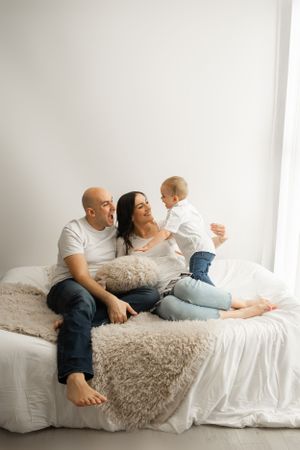 Family enjoying playful moment together on cozy white bed.