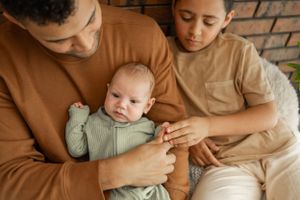 Intimate family portrait with brown and beige tones against brick wall backdrop.