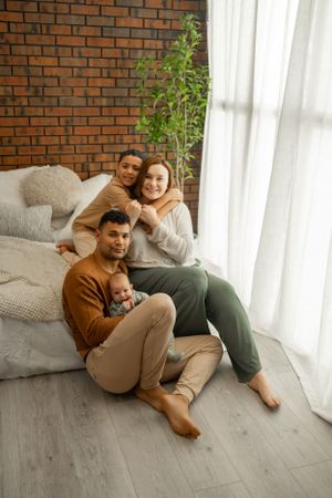 Casual family photo session with exposed brick wall and soft window lighting.
