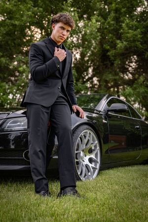 a young man in tux with car