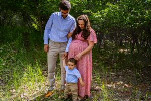 a toddler standing with his parents.