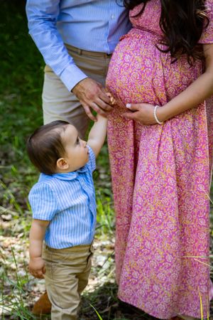 a toddler standing with his parents.